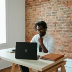 man sat at desk looking at laptop