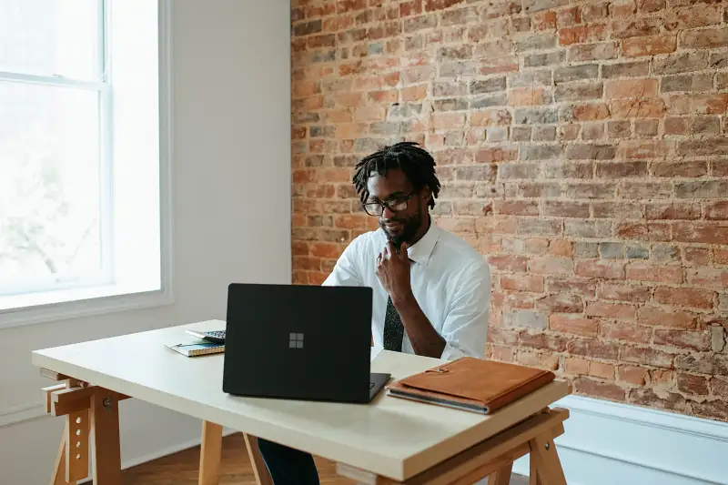 man sat at desk looking at laptop