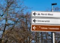 A street sign pointing towards a german university