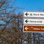 A street sign pointing towards a german university
