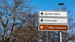 A street sign pointing towards a german university