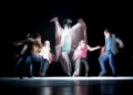 five blurred people enacting a stage performance