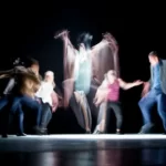 five blurred people enacting a stage performance