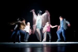 five blurred people enacting a stage performance