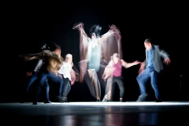 five blurred people enacting a stage performance