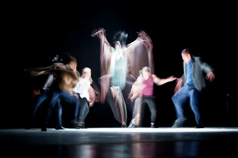 five blurred people enacting a stage performance