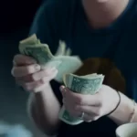 a woman holding a wad of dollar bills - income inequality capitalism