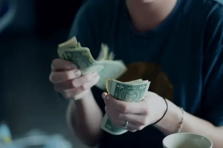 a woman holding a wad of dollar bills - income inequality capitalism