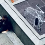 homeless man sat on a piece of cardborad - inequality and poverty