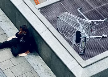 homeless man sat on a piece of cardborad - inequality and poverty
