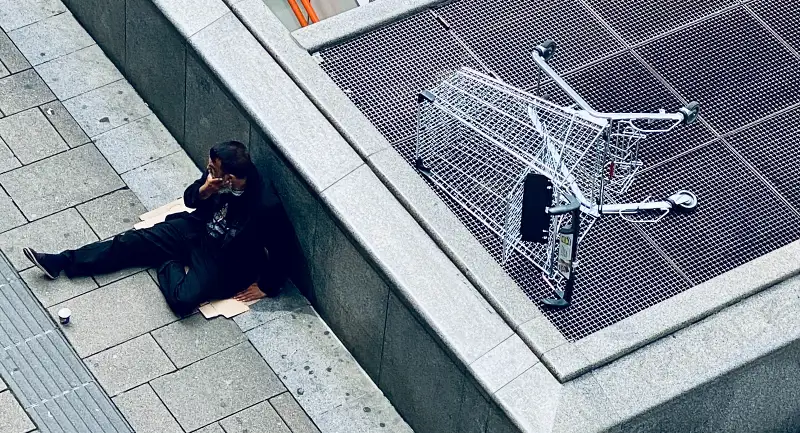 homeless man sat on a piece of cardborad - inequality and poverty