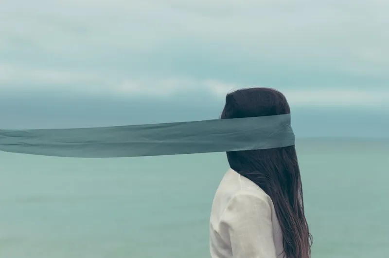 an artistic shot of a woman with a blindfold on which extends backwards out of shot. avoidance relationships
