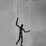 A hand holding a puppet on a string
