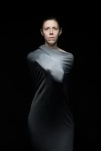 A person set against a black background bounded in a garment
