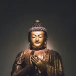 The Buddha with a spotlight on his face and a dark background