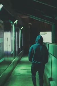 a hooded person walking through a dark tunnel