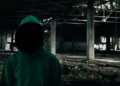 a faceless and hooded social actor in an abandoned building