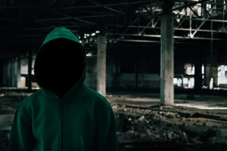 a faceless and hooded social actor in an abandoned building