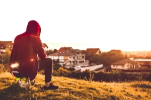 a man sat looking over a field at sunset