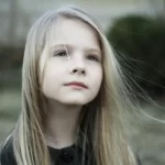 A girl with blond hair looking thoughtful