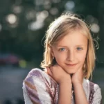 A young blonde girl with her head in her hands