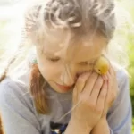 A child seeking comfort from a little yellow duckling