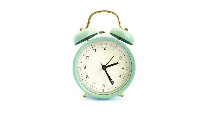 green alarm clock against a white background