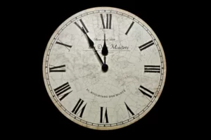 A white clock against a black background. It has roman numerals and displays the time as 11:55