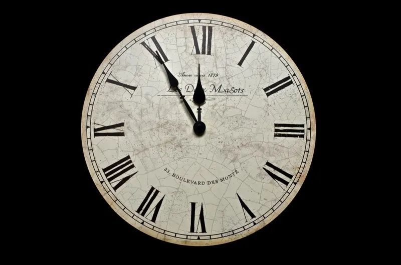 A white clock against a black background. It has roman numerals and displays the time as 11:55