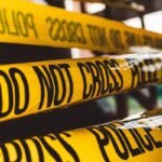 yellow police tape with black writing saying 'do not cross' - crime and deviance