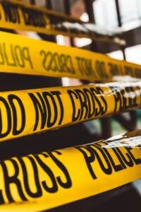 yellow police tape with black writing saying 'do not cross' - crime and deviance