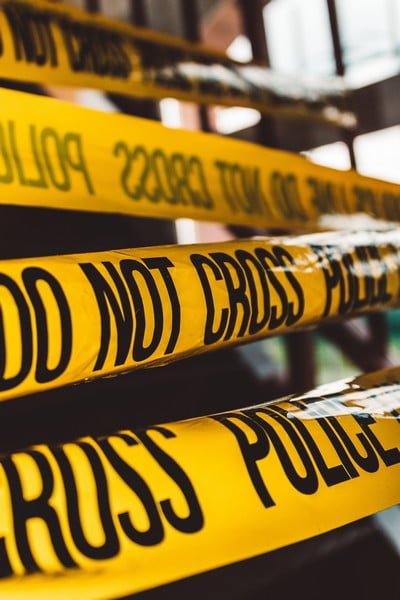 yellow police tape with black writing saying 'do not cross' - crime and deviance