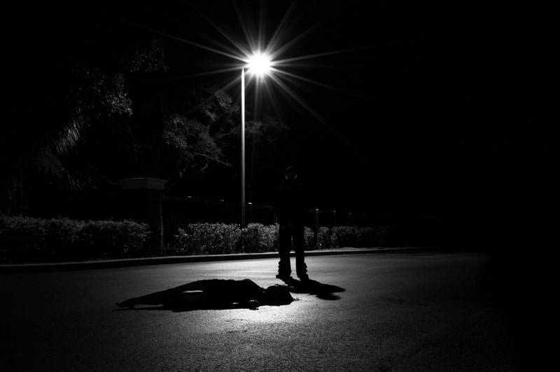 A shadowy deviant dangerous classes figure under a streetlight