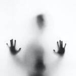 A figure behind a white screen