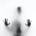 A figure behind a white screen