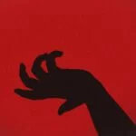 An overly dramatic black hand against a red background