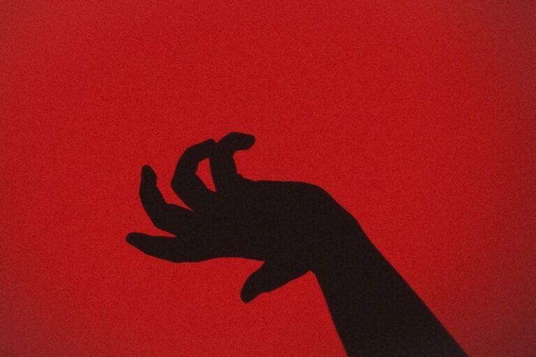 An overly dramatic black hand against a red background