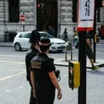 two police waiting to cross the road