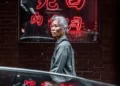 A japanese woman walking past a neon red japanese sign