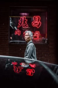 A japanese woman walking past a neon red japanese sign