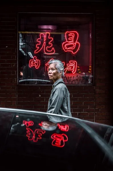 A japanese woman walking past a neon red japanese sign
