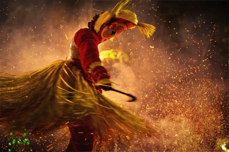 A fire-enveloped person wearing cultural dress and performing a cultural dance