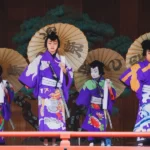 4 japanese people at a festival wearing kimonos and holding traditional sun umbrellas