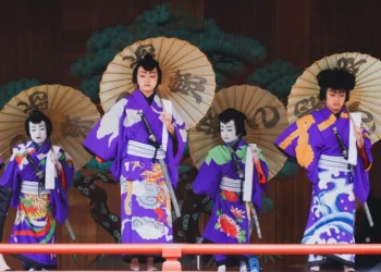 4 japanese people at a festival wearing kimonos and holding traditional sun umbrellas