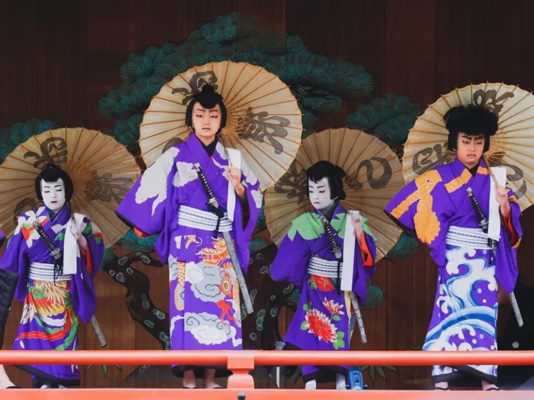 4 japanese people at a festival wearing kimonos and holding traditional sun umbrellas
