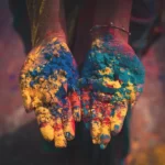 a pair of hands covered in cultural colours of paint