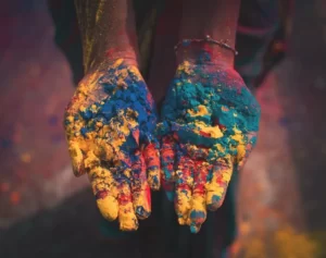 a pair of hands covered in cultural colours of paint