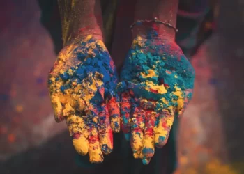 a pair of hands covered in cultural colours of paint