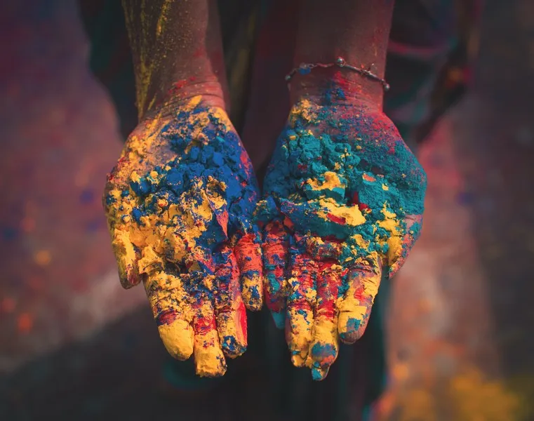 a pair of hands covered in cultural colours of paint