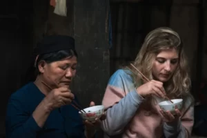 Two women of differing ethnicities sharing a bowl of cultural food
